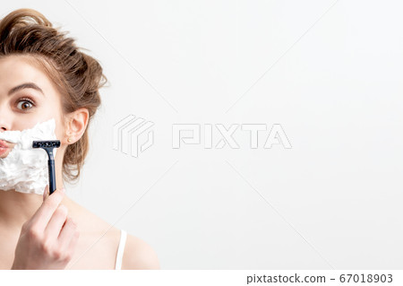 Woman shaving her face by razor 67018903