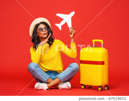 Ethnic traveler playing with toy plane. 67019053