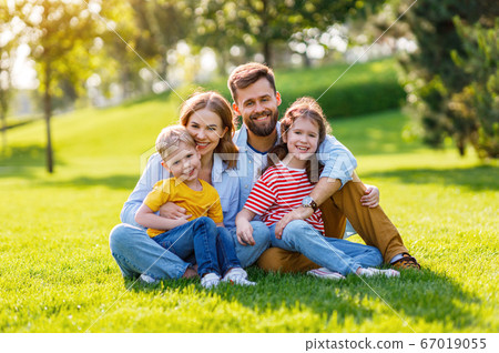 Delighted family hugging on lawn. 67019055