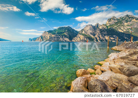 Lake Garda with surfers and high mountains in background, Italy 67019727