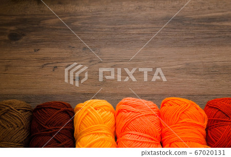 A row of yarn on a brown wooden table 67020131