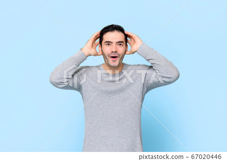 Shocked handsome Caucasian man gasping and holding his head  67020446