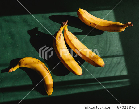 Bananas on a green background. Summer abstract creative photography with sun light and shadows. Bananas on a green background. Summer abstract creative photography with sun light and shadows. 67021876