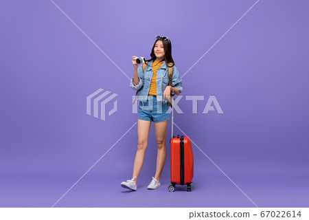 Young smiling Asian tourist girl with camera and baggage Young smiling Asian tourist girl with camera and baggage 67022614
