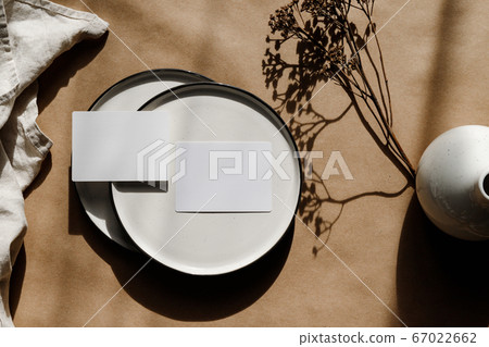 Two blank paper sheet card on a bowl. Minimalist ceramics set over a linen cloth. Business template, copy space, flat lay. 67022662