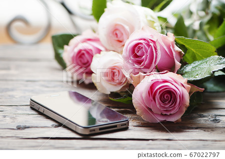 Pink roses and smartphone on the wooden table 67022797