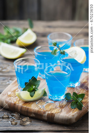 Blue curacao liqueur with lemon on the wooden Blue curacao liqueur with lemon on the wooden 67023650
