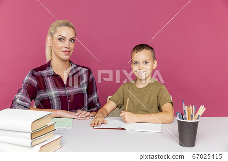 Homework together at quarantine concept. Mother with kid sitting at the desk with books and studying. Homework together at quarantine concept. Mother with kid sitting at the desk with books and studying. 67025415