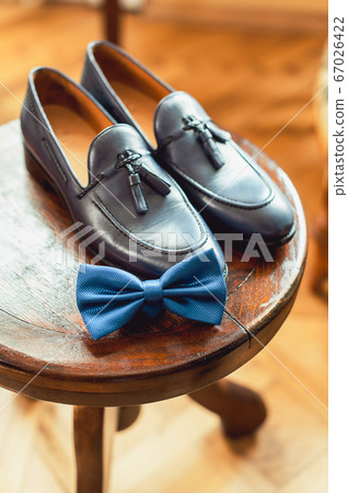 Blue shoes and bow tie on a wooden round stool. Accessory for formal dress. Symbol of elegance and fashion for men. 67026422