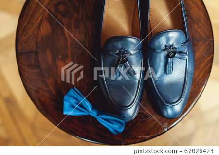 Blue shoes and bow tie on a wooden round stool. Accessory for formal dress. Symbol of elegance and fashion for men. 67026423