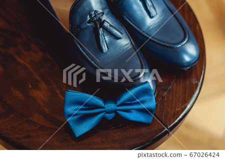 Blue shoes and bow tie on a wooden round stool. Accessory for formal dress. Symbol of elegance and fashion for men. 67026424