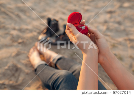 female's hand hold gift box with golden engagement 67027014