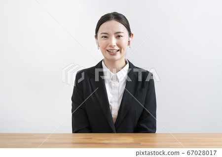 A young woman in a suit wearing wireless headphones and talking from the camera's perspective 67028017