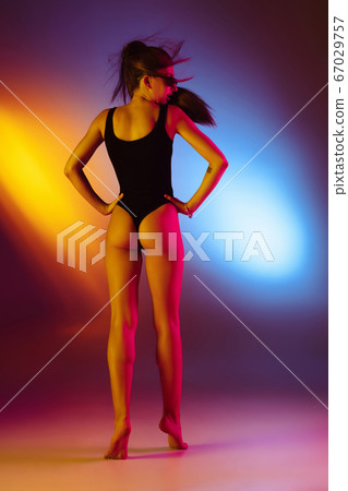 Beautiful seductive girl in fashionable swimsuit on disco bicolored neon studio background in neon light. Summer, resort, fashion and weekend concept Beautiful seductive girl in fashionable swimsuit on disco bicolored neon studio background in neon light. Summer, resort, fashion and weekend concept 67029757