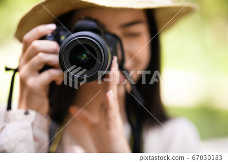 Young asian girl taking photos in the park with modern camera, closeup 67030183