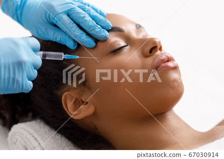 Black woman getting eye injection at salon 67030914