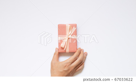 Hand holding pink gift box on white background. top view, copy space 67033622