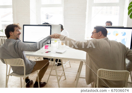 Friendly colleagues fist bumping celebrating success and good te 67036074