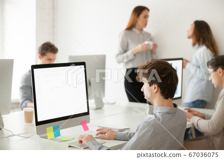 Young male employee working on computer writing email in office 67036075