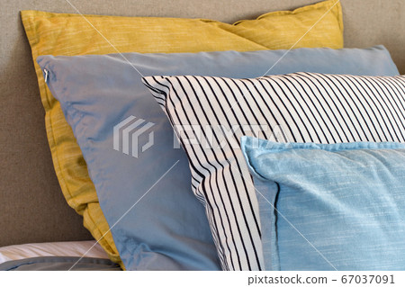 Closeup of Yellow and light blue pillows in a row on the bed, modern retro decoration for home, pastel light colors colorful bright Closeup of Yellow and light blue pillows in a row on the bed, modern retro decoration for home, pastel light colors colorful bright 67037091