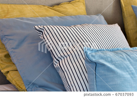 Closeup of Yellow and light blue pillows in a row on the bed, modern retro decoration for home, pastel light colors colorful bright Closeup of Yellow and light blue pillows in a row on the bed, modern retro decoration for home, pastel light colors colorful bright 67037093
