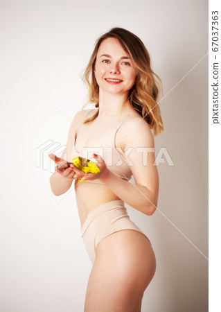 Beautiful young woman with a beautiful figure measures her waist with a measuring tape Beautiful young woman with a beautiful figure measures her waist with a measuring tape 67037363