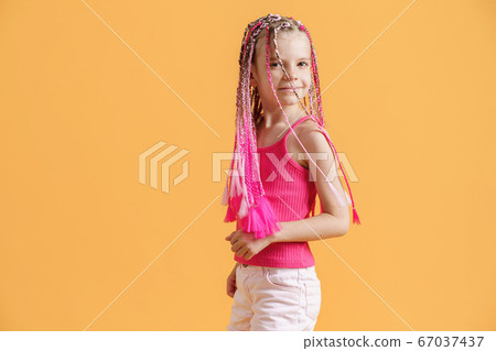Stylish girl with pink dreadlocks and posing on a yellow background. Beauty, fashion. 67037437