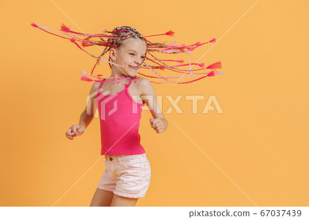 Stylish girl with pink dreadlocks and posing on a yellow background. Beauty, fashion. 67037439