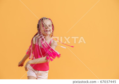 Stylish girl with pink dreadlocks and posing on a yellow background. Beauty, fashion. 67037445
