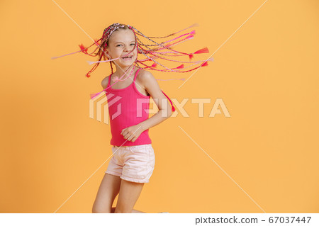 Stylish girl with pink dreadlocks and posing on a yellow background. Beauty, fashion. 67037447