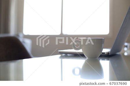 White coffee mug beside laptop computer 67037690