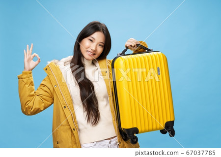 Cheerful woman of Asian appearance yellow suitcase on vacation Cheerful woman of Asian appearance yellow suitcase on vacation 67037785