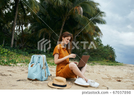 Woman in the sand with hat and backpack laptop work fun freelancer  67037898