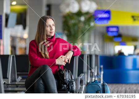 Young woman sitting at airport waiting for flight Young woman sitting at airport waiting for flight 67038195
