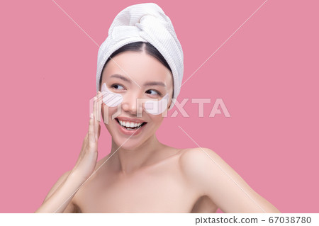 Smiling woman using new anti-ageing eye patches Smiling woman using new anti-ageing eye patches 67038780