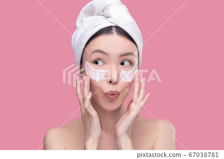 Woman using hyaluronic eye-patches for under eyes zone Woman using hyaluronic eye-patches for under eyes zone 67038781