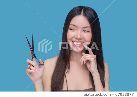 Smiling young long-haired woman thinking about haircut 67038877