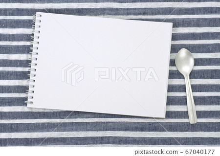 A sketchbook and a spoon placed on a placemat A sketchbook and a spoon placed on a placemat 67040177