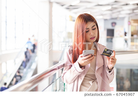 asian young woman red hair holding smartphone and credit card. asian young woman red hair holding smartphone and credit card. 67045907