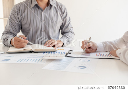 Two business leaders discussing the charts and graphs showing the results, Planning to start a new strategy for big success Two business leaders discussing the charts and graphs showing the results, Planning to start a new strategy for big success 67049880