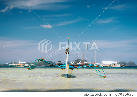 Traditional banca boat in clear water at sandy Corong Beach in El Nido, Philippines. Low angle view Traditional banca boat in clear water at sandy Corong Beach in El Nido, Philippines. Low angle view 67050653