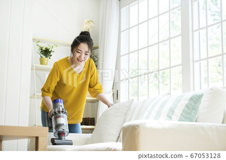 Young woman cleaning the sofa 67053128