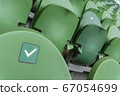 Empty plastic seats in a stadium. Stickers intended to promote social distancing in the arena. 67054699