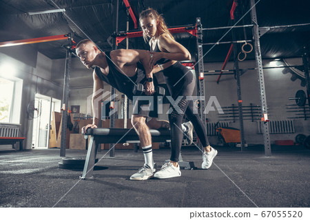 Beautiful young sporty couple training, workout in gym together 67055520