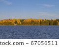 Autumn forest on the shore of the lake with blue water 67056511