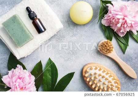 Concept SPA and Wellness. Massage brush, cosmetic oils and soap. Light background with peony flowers. Copy space 67056925
