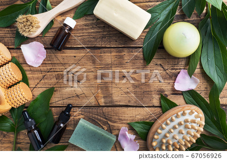Concept SPA and Wellness. Massage brush, cosmetic oils and soap. Wooden background with green leaf. Copy space 67056926