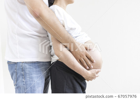 A pregnant woman and her husband touching their stomachs A pregnant woman and her husband touching their stomachs 67057976