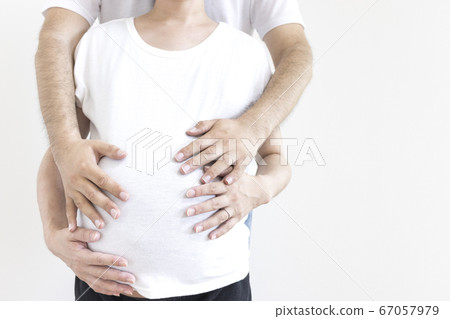 A pregnant woman and her husband touching their stomachs A pregnant woman and her husband touching their stomachs 67057979