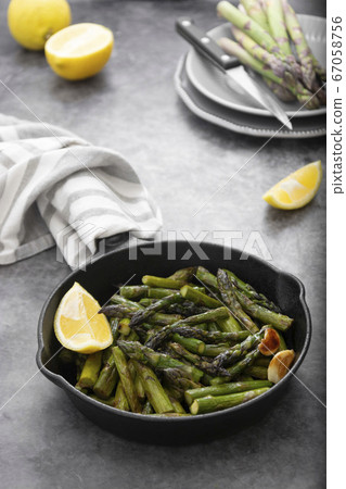 Fresh green roasted asparagus in black iron pan. 67058756